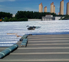 On-site construction shot of VMPET fabric laid under metal roof tiles to reflect solar heat and cut building energy consumption