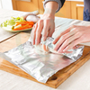 Hands wrapping cooked meat or snacks with aluminum foil, demonstrating excellent flexibility and ease of use for food storage.