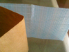 Folded close-up of printed woven tape with thick kraft release liner, easy peel for carpet binding on wood & tile floors